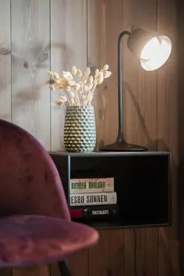 a lamp and a vase on a shelf with books at Luxurious 5-Bedroom Mountain Chalet with Sauna, Panoramic Views, and Two Full Bathrooms in Stranda
