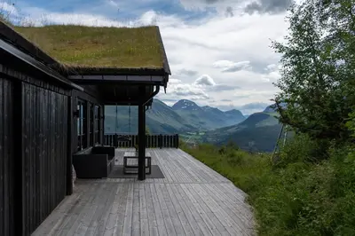 a building with a grass roof with a wooden walkway at Luxurious 5-Bedroom Mountain Chalet with Sauna, Panoramic Views, and Two Full Bathrooms in Stranda