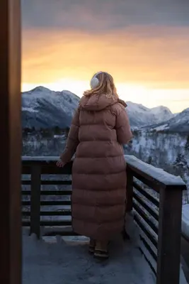 a woman standing on a bench in the snow at Dream Cabin Mivo X - Mountain Views and Idyllic Location at Strandafjellet in Stranda