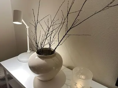 a white vase on a table with a lamp and a candle at Apartments Bergen with sea view! in Bergen