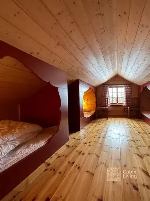 an attic room with a bed and a wooden floor at Large cabin with Sjusjøens best view, sauna and ski in out in Ringsaker
