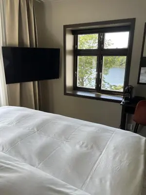 a bedroom with a white bed and a window at Biologen Herdla in Askøy