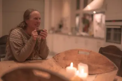 a woman sitting at a table taking a picture with her cell phone at Monshaugen Home - Privat Retreat in Sykkylven