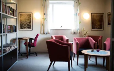 a waiting room with chairs and a table and a window at Sitla Hotel & Apartments in Øvre Årdal