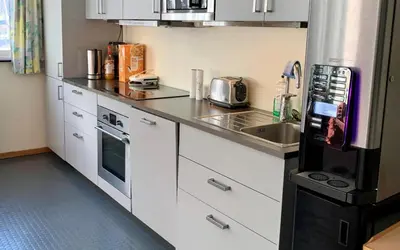a kitchen with white cabinets and a black refrigerator at Sitla Hotel & Apartments in Øvre Årdal