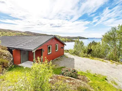 a red house on a hill next to a body of water at 6 person holiday home in Ånneland-By Traum in Ånneland