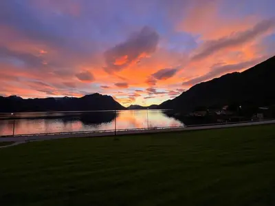 a sunset over a body of water with mountains at Enesi holiday house in Hestenesøyra