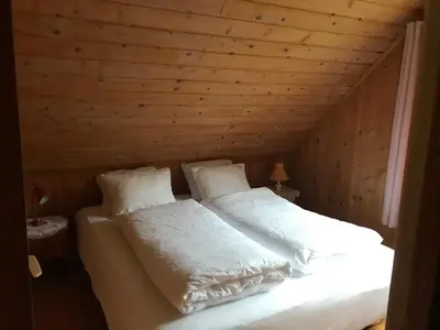 a bed in a wooden room with white sheets and pillows at Enesi holiday house in Hestenesøyra