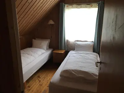 two beds in a small room with a window at Enesi holiday house in Hestenesøyra
