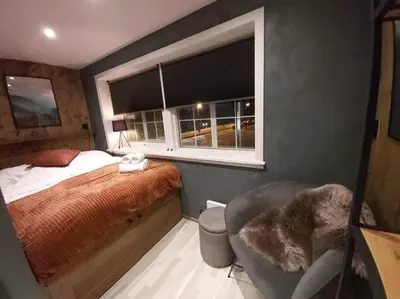 a bedroom with a bed and a chair and a window at Fossheim Lodge Nr 10 in Torset