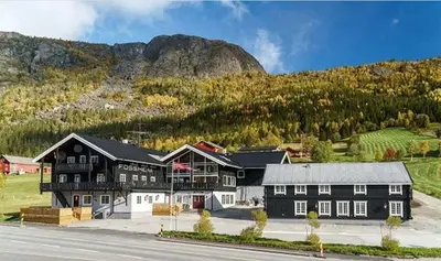 a large black and white building in front of a mountain at Fossheim Lodge Nr 10 in Torset