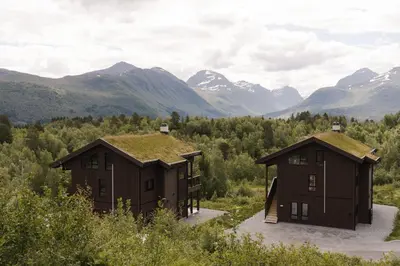 two buildings with grass on their roofs in the mountains at Ground Floor Exclusive Apartment with Sauna - Near Geiranger and the Norwegian Fjords in Stranda