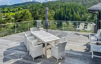 a wooden deck with a table and chairs and an umbrella at Beach Front Home In Førde I Hordaland in Erve