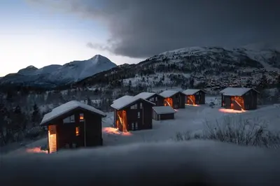 a row of lodges in the snow at night at Exclusive Nordic Apartment with Sauna - Prime Location at Stranda near Geiranger in Stranda
