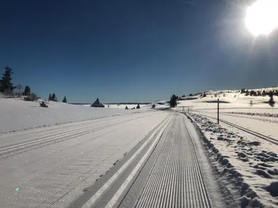 a snow covered road with the sun in the sky at Bualie - Golsfjellet - Biking, swimmming, hiking. High standard. in Gol