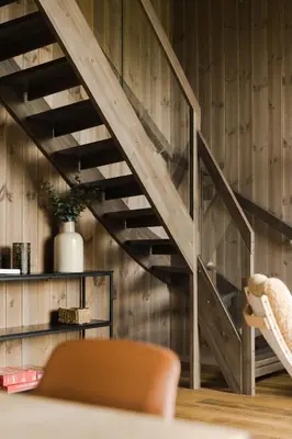 a wooden staircase in a living room with a chair at Nordic Luxury Apartment - Private Sauna & Panoramic Mountain Views in Stranda