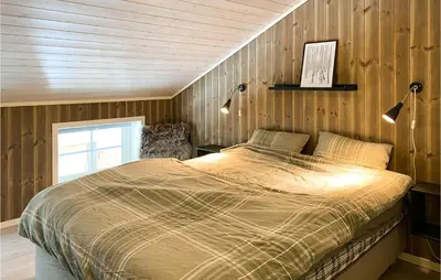 a bed in a bedroom with a wooden wall at Amazing Home In Nordfjordeid With Wifi in Nordfjordeid