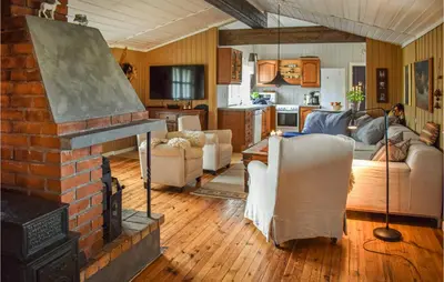 a living room with a brick fireplace and a kitchen at Nice Home In Tuddal With Kitchen in Tuddal