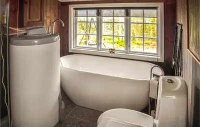 a bath tub in a bathroom with a window and a toilet at Nice Home In Tuddal With Kitchen in Tuddal