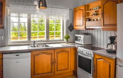 a kitchen with wooden cabinets and a sink and a microwave at Nice Home In Tuddal With Kitchen in Tuddal
