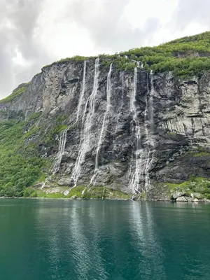 a mountain with waterfalls on the side of a lake at Beach front appartments in design eco-villa in Ulsteinvik