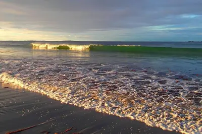 a wave in the ocean on a sandy beach at Beach front appartments in design eco-villa in Ulsteinvik