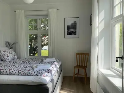 a bedroom with a bed and a chair and a window at Valldal Sentrum Overnatting in Valldal