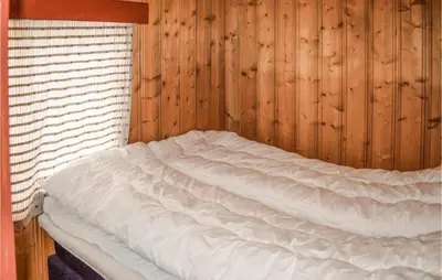 a bed in a room with a wooden wall at Nice Home In Rauland With Kitchen in Rauland