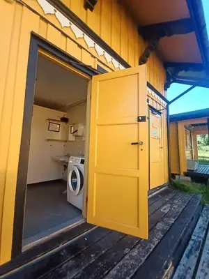 a yellow door on the side of a house with a washing machine at LUBBENES GÅRD in Molde