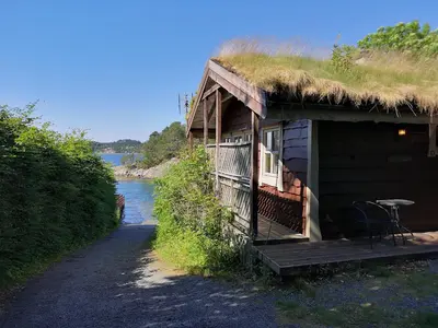 a hut with a grass roof with a table on the porch at Fanafjorden Cabins in Bergen