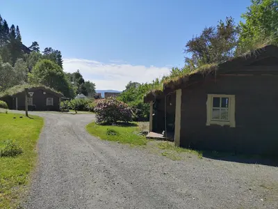 a dirt road next to a house with a grass roof at Fanafjorden Cabins in Bergen