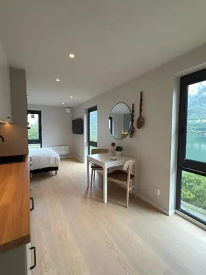 a bedroom with a bed and a table and a mirror at Odda City Apartments in Odda