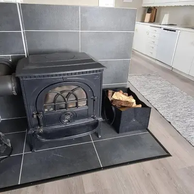 a black stove in a kitchen with a floor at Koselig hus med hage i Herøy på Sunnmøre. in Røyra