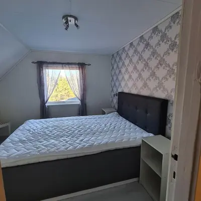 a bedroom with a large bed with a window at Koselig hus med hage i Herøy på Sunnmøre. in Røyra