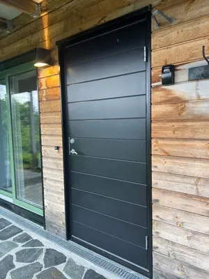 a black garage door on the side of a house at Fin leilighet med parkering! in Bergen