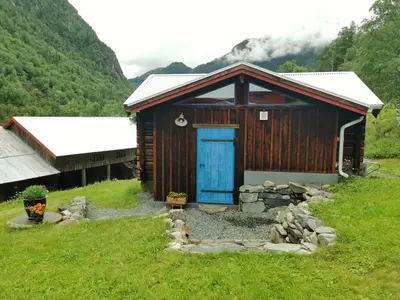 a wooden cabin with a blue door in a field at Unique farm stay in the steep mountains of Rjukan in Vemork