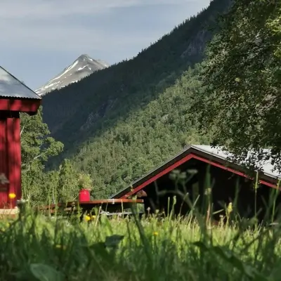 a red barn with a mountain in the background at Unique farm stay in the steep mountains of Rjukan in Vemork