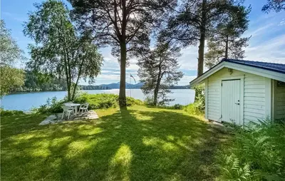 a small shed in the grass next to a lake at 4 Bedroom Beach Front Home In Skodje in Skodje