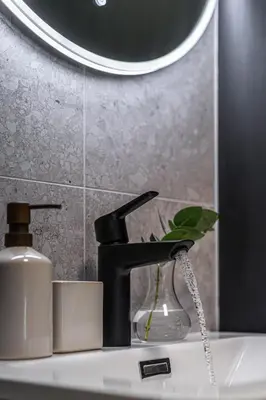 a bathroom sink with a black faucet and a mirror at Charming and bright apartment in Ålesund city in Ålesund