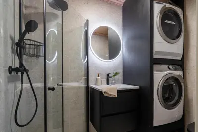 a bathroom with a shower and a washing machine at Charming and bright apartment in Ålesund city in Ålesund