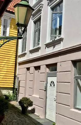 a pink house with a white door and a street light at Knøsesmauet Apartment in Bergen