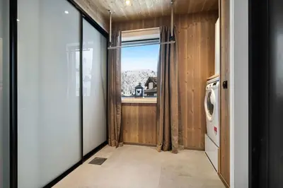 a small kitchen with a window and a laundry room at Ski-in-out from the door Alpine XC Mountain views in Torvetjørn