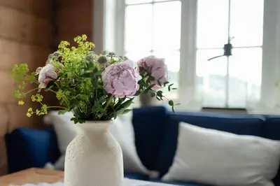 a white vase filled with pink flowers on a table at Vakker leilighet - stor parkeringsplass 10min fra Bergen in Bergen