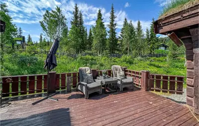 a wooden deck with two chairs and an umbrella at Nice Home In Svingvoll in Svingvoll