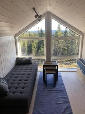 a living room with a couch and a large window at Sykkelhytte ved Slåtten i Synnfjellet in Nord Torpa