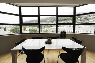 a white table and chairs in a room with large windows at Beautiful apartment with 3 bedrooms in Sogndal