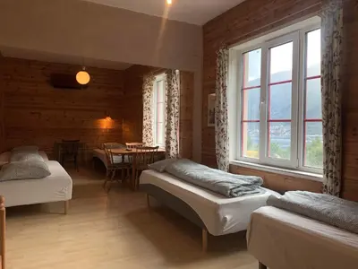 a bedroom with two beds and a dining room with a table at Fjordshelter dorm in Tysso
