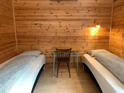a room with two beds and a table in a cabin at Fjordshelter dorm in Tysso