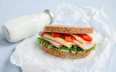 a sandwich with meat cheese and lettuce and a bottle of milk at Flexbase in Brekstad