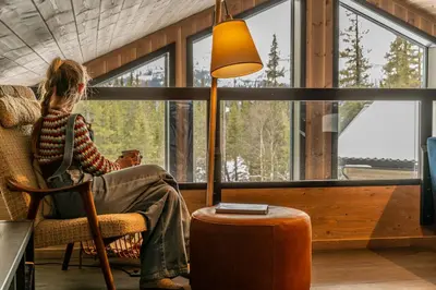 a woman sitting in a chair in a room with a lamp at Private Room in Beautiful Mountain Home w/ Sauna in Beitostøl
